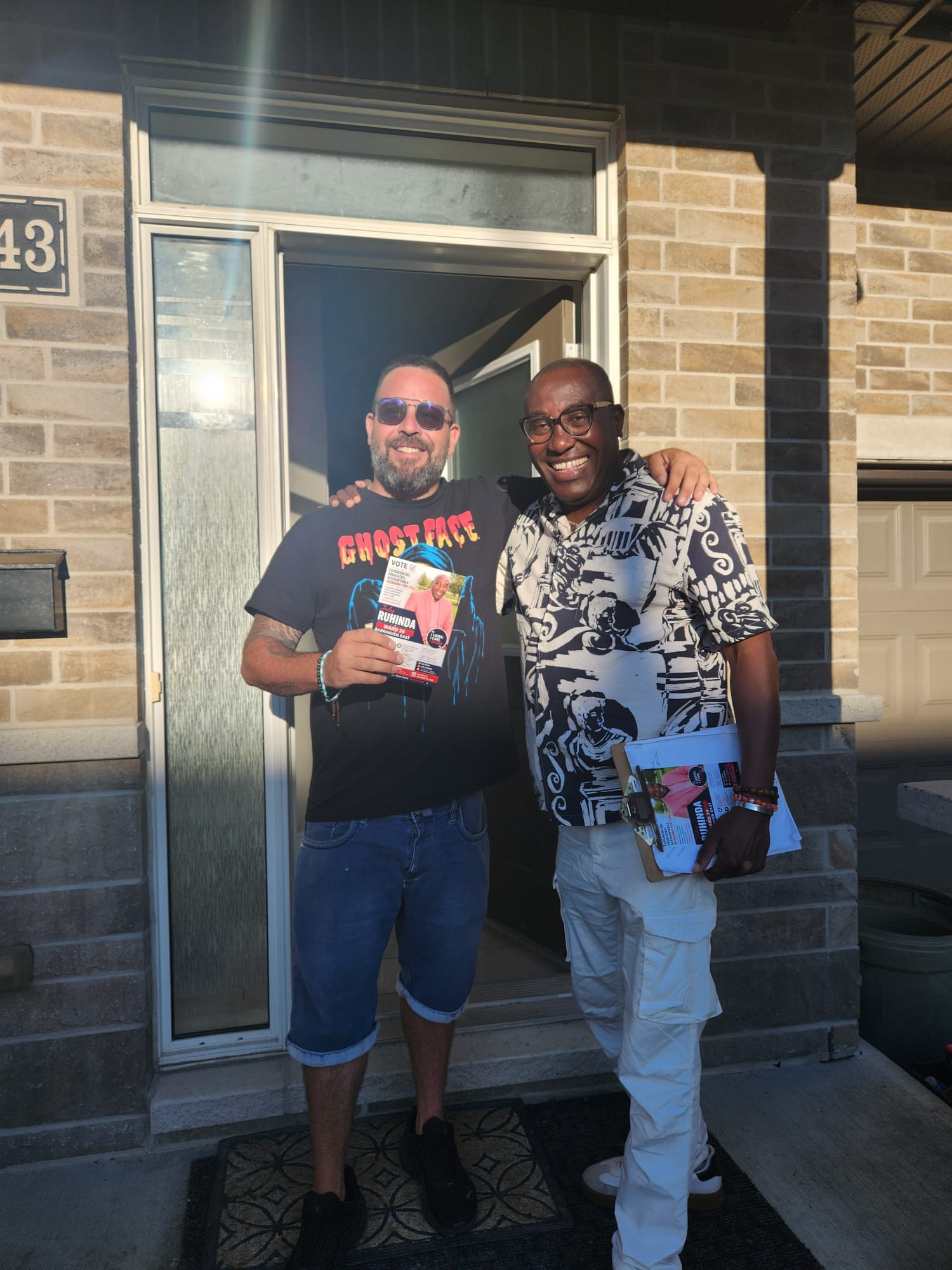 Jules Ruhinda with a Barrhaven East resident holding a campaign flyer